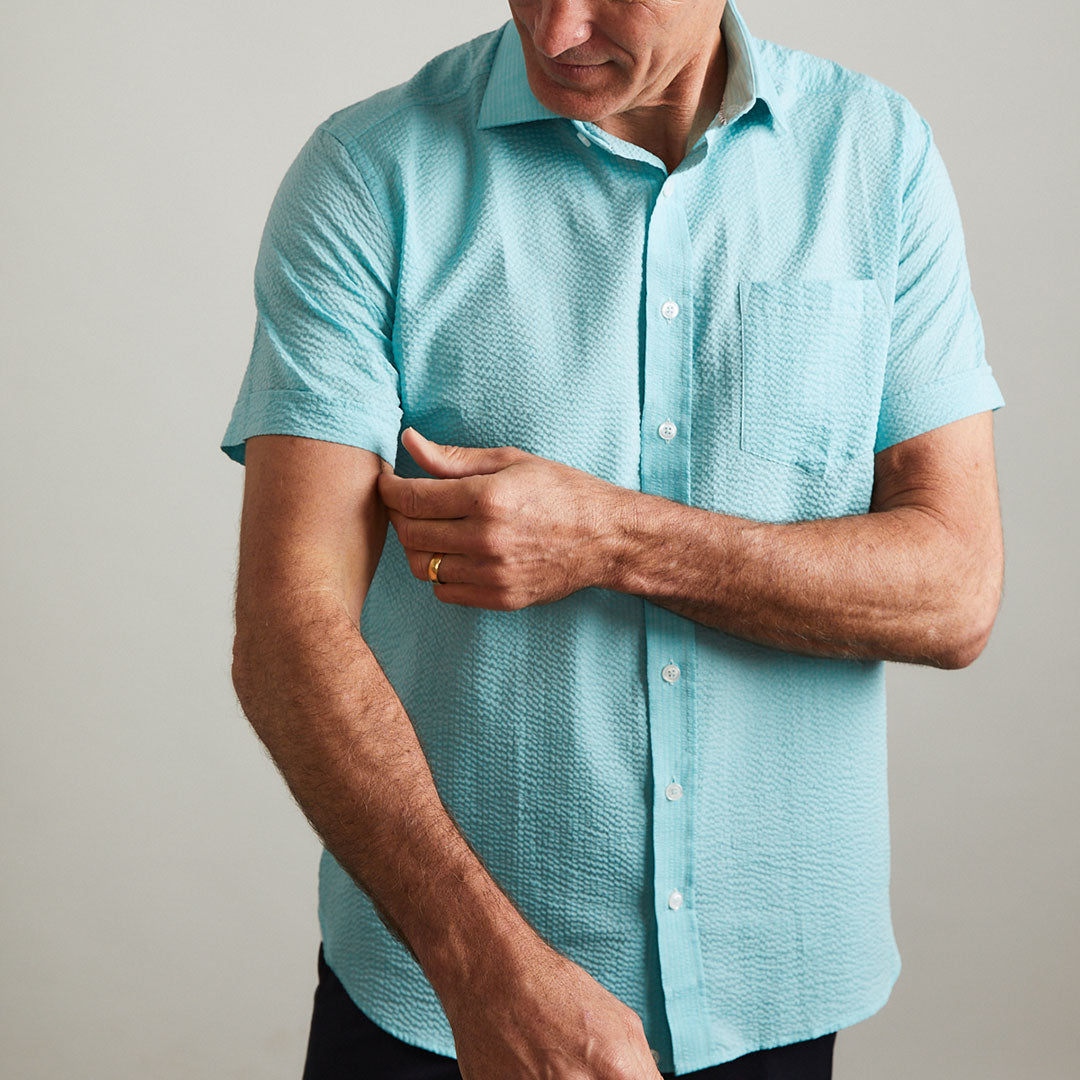 A solid look for a solid guy. The light teal hues of the ocean are calling you in this shirt. Seersucker, lightweight, and supremely cool. Available in short or long sleeve.  100% Cotton Seersucker  •  Spread Collar  •  Short Sleeve  •  Contrast Buttons  •  Chest Pocket  •  Machine Washable  •  Made in Italy