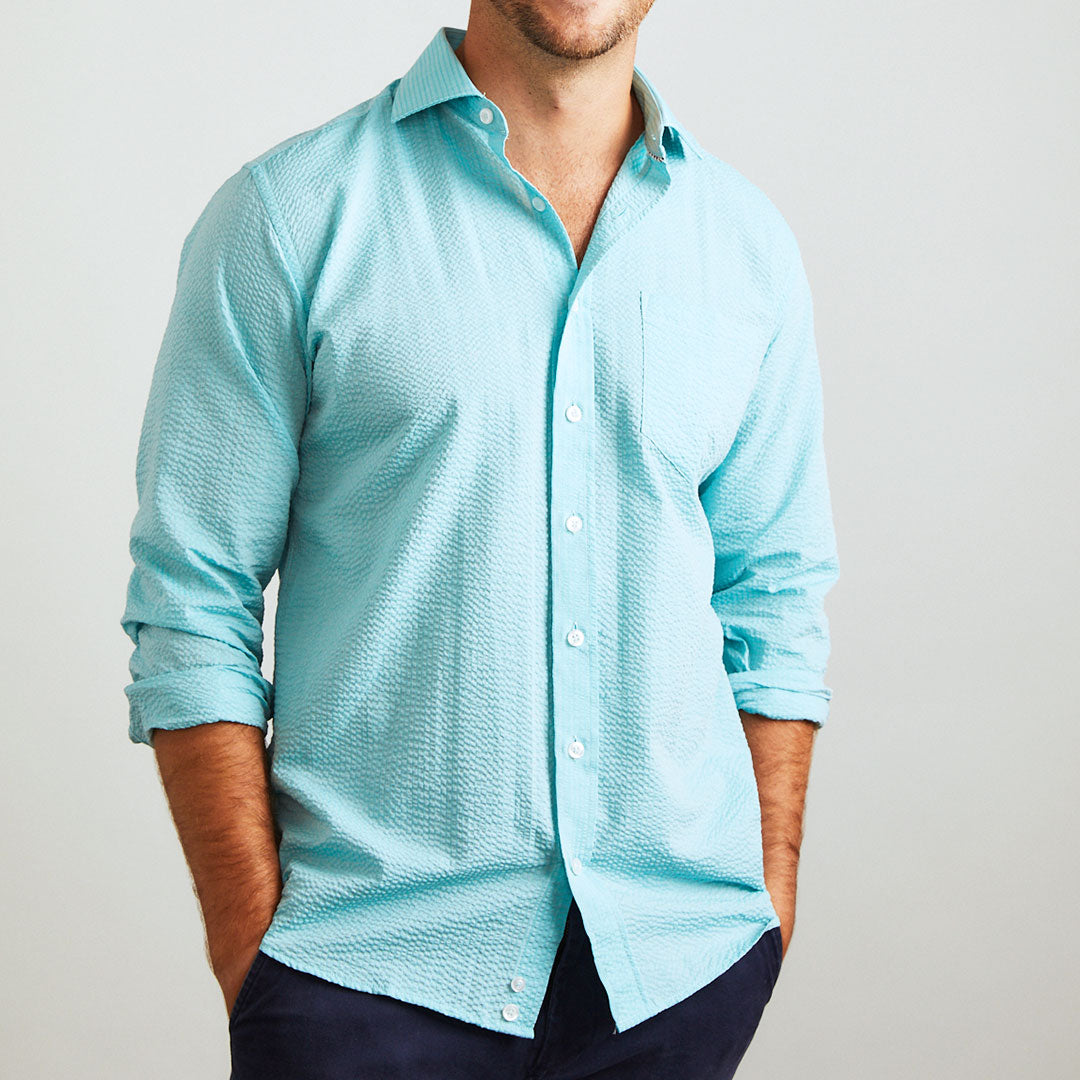 A solid look for a solid guy. The light teal hues of the ocean are calling you in this shirt. Seersucker, lightweight, and supremely cool. Available in short or long sleeve.  100% Cotton Seersucker  •  Spread Collar  •  Long Sleeve  •  Chest Pocket  •  Machine Washable  •  Made in Italy 