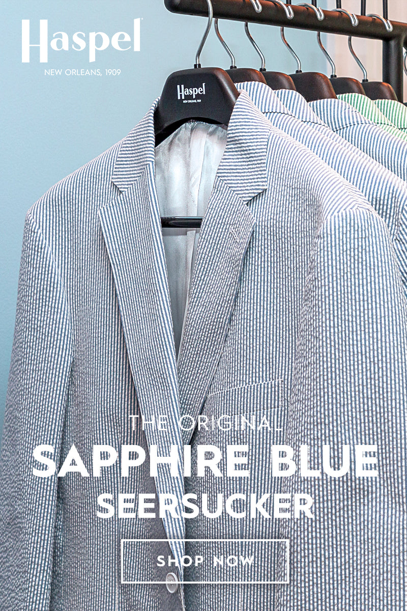 Sapphire Blue seersucker suit jacket on a hanger with 'Haspel' branding against a light blue background. Heading reads The Original Sapphire Blue Seersucker and a Shop Now button.