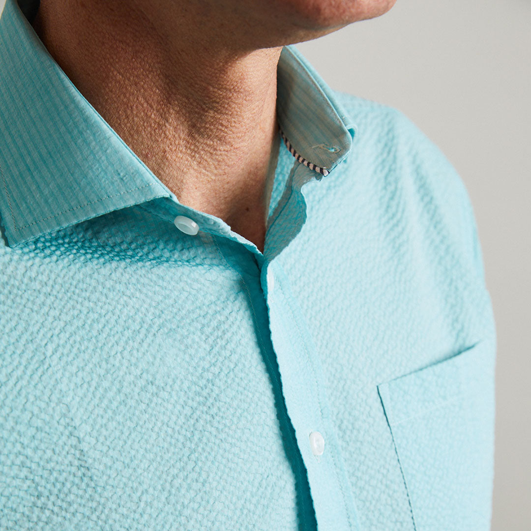 A solid look for a solid guy. The light teal hues of the ocean are calling you in this shirt. Seersucker, lightweight, and supremely cool. Available in short or long sleeve.  100% Cotton Seersucker  •  Spread Collar  •  Short Sleeve  •  Contrast Buttons  •  Chest Pocket  •  Machine Washable  •  Made in Italy